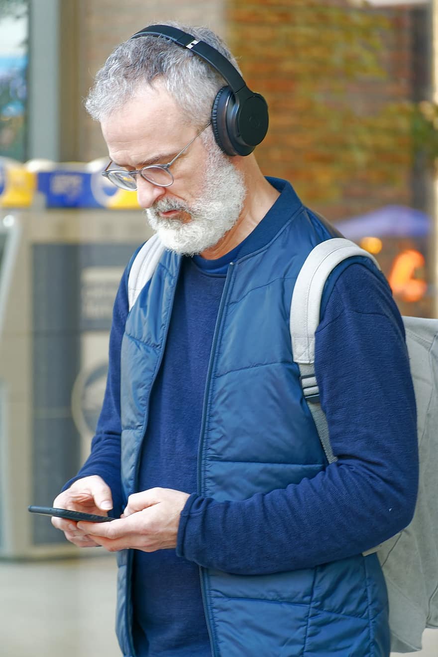 Старий чоловік, навушники, смартфон