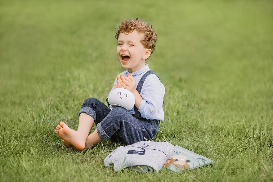 Laughing, One Person, Barefoot, Color Image, Sitting, Grass, Outdoors, Happiness, Child, Enjoyment, Childhood