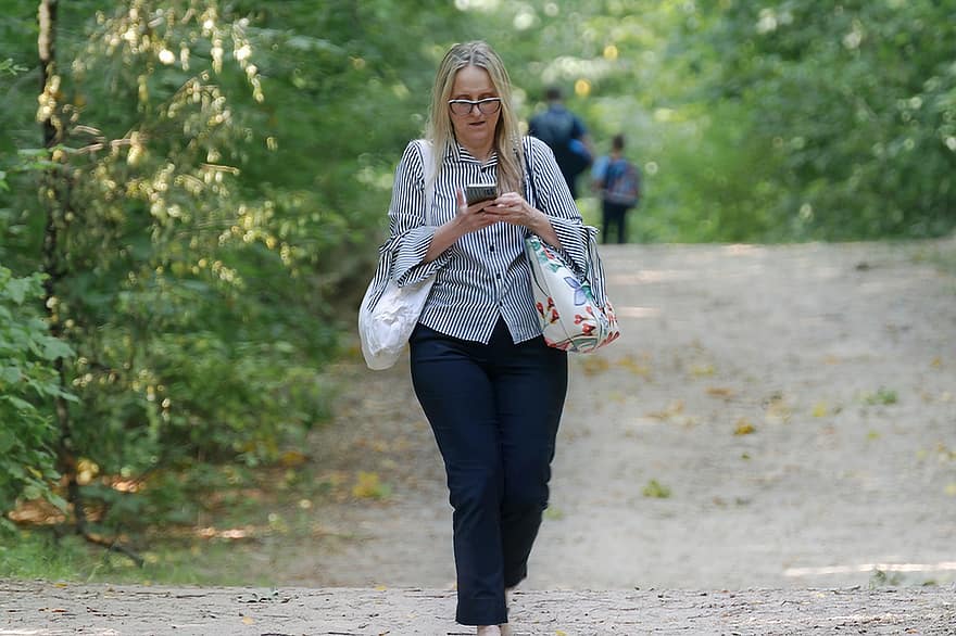 femme, textos, en marchant, téléphone intelligent, forêt